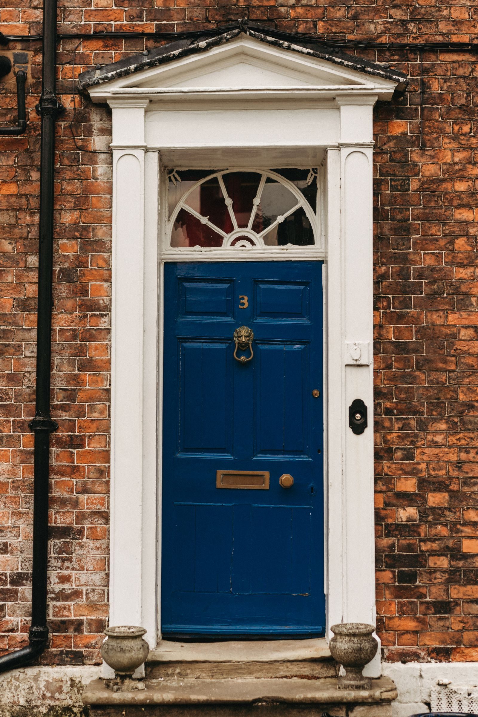 A classic blue panelled composite front door in a brick terrace