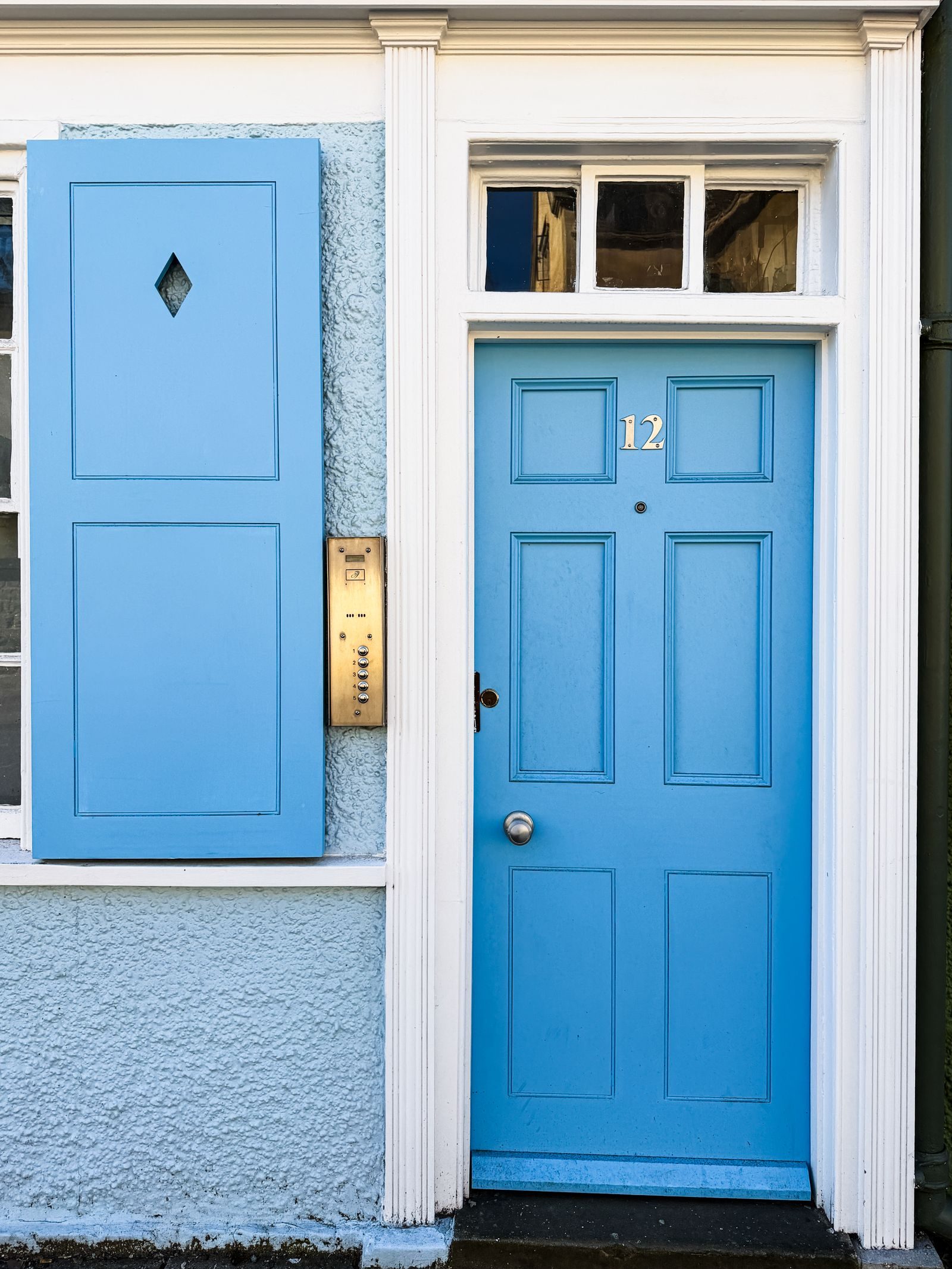 A blue front door with a glazed top light and matching surround