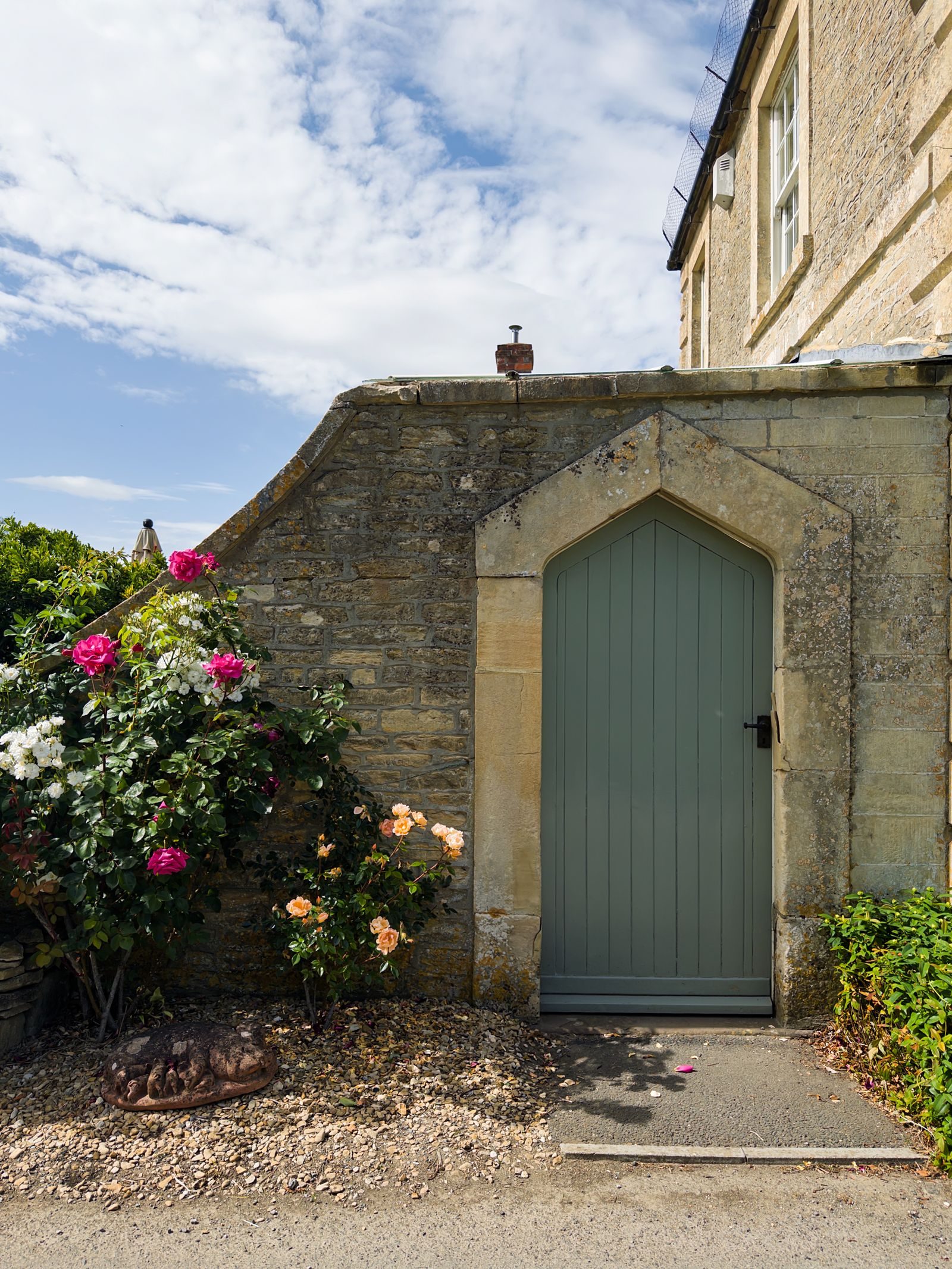 A sage green cottage-style plank door set in a stone wall